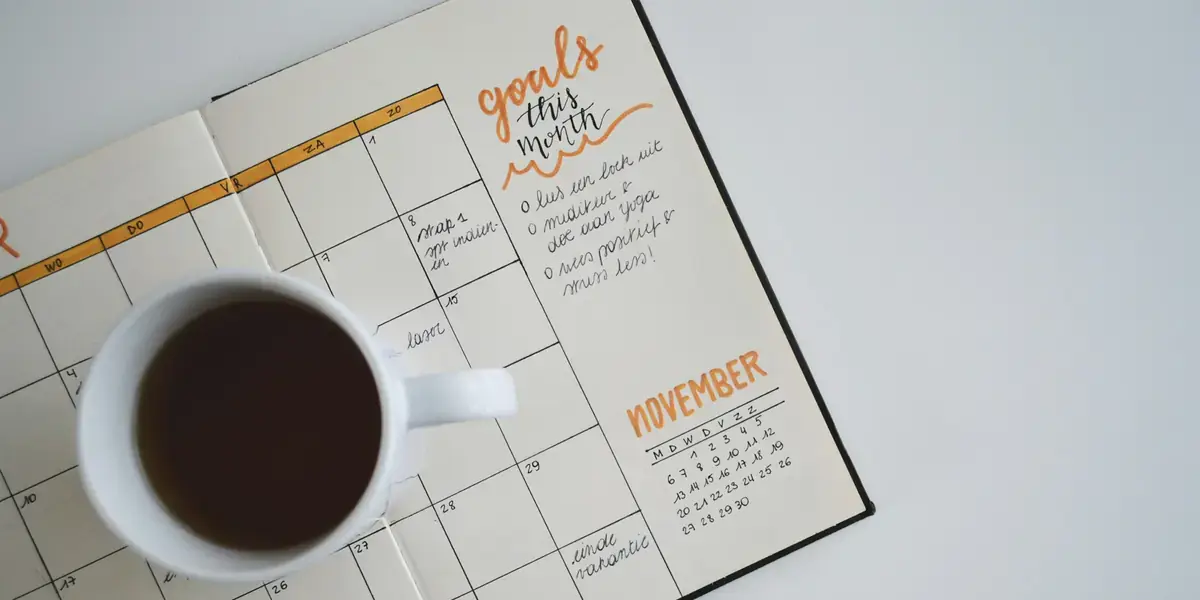 Agenda mensual abierta sobre una mesa junto a una taza de café