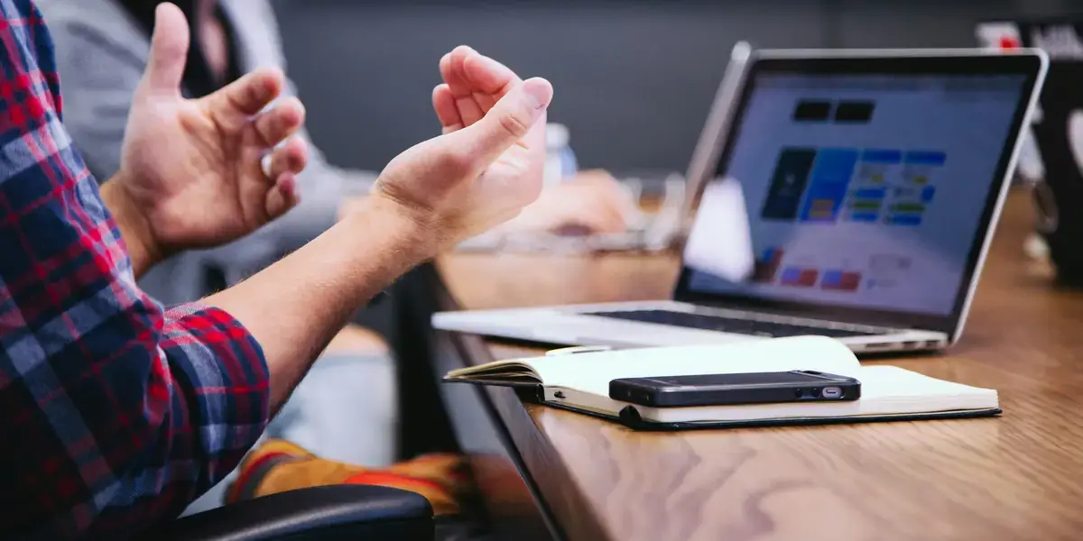 Reunión de trabajo con varias personas alrededor de una mesa con portátiles