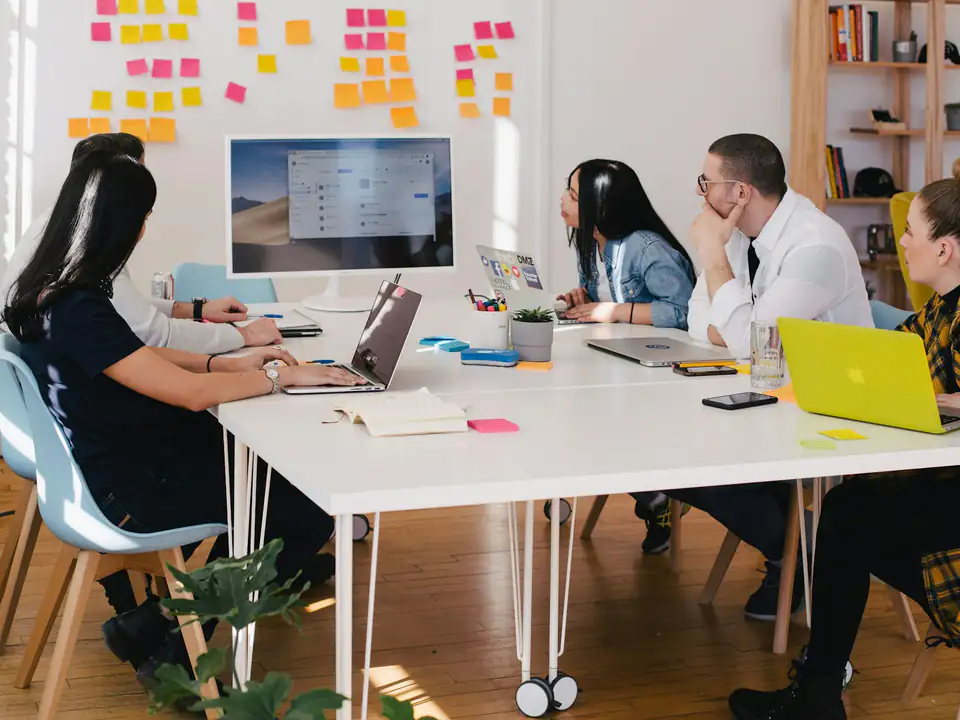 Equipo reunido alrededor de una mesa de trabajo con portátiles y notas adhesivas